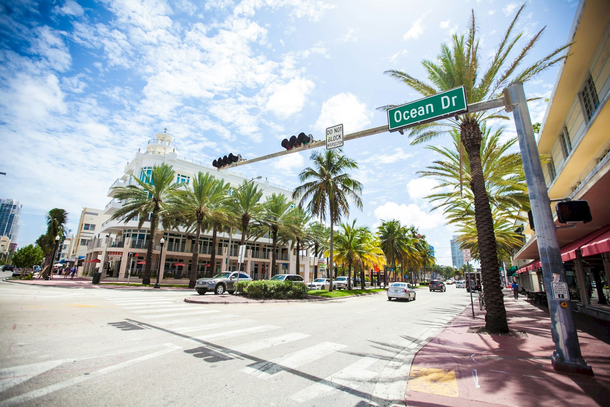 The image shows a sunny street scene with palm trees, buildings, and a street sign for Ocean Drive under a blue sky.
